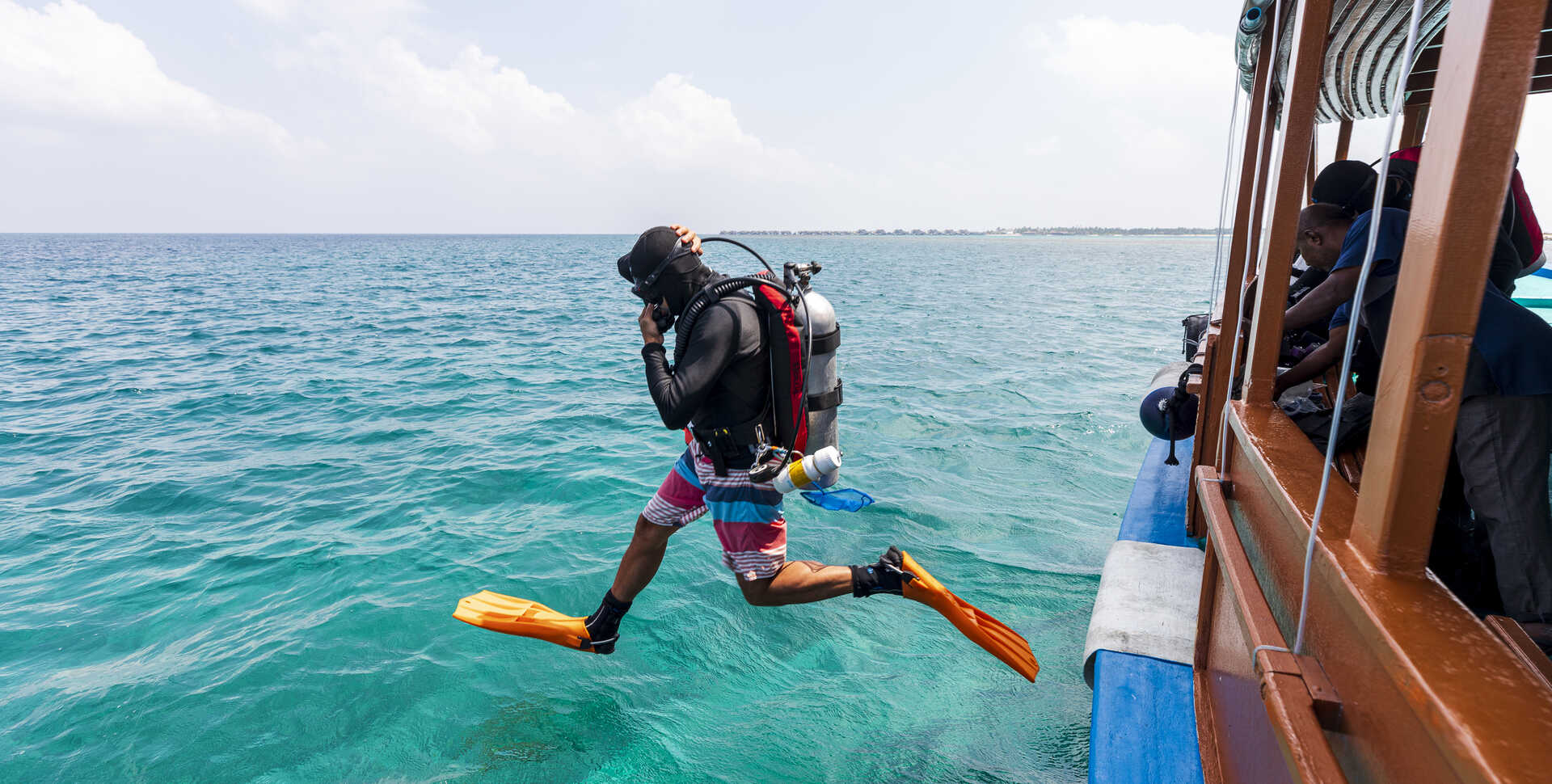Academy ichthyologist Luiz Rocha in mid-air as he steps off dive boat in the Maldives